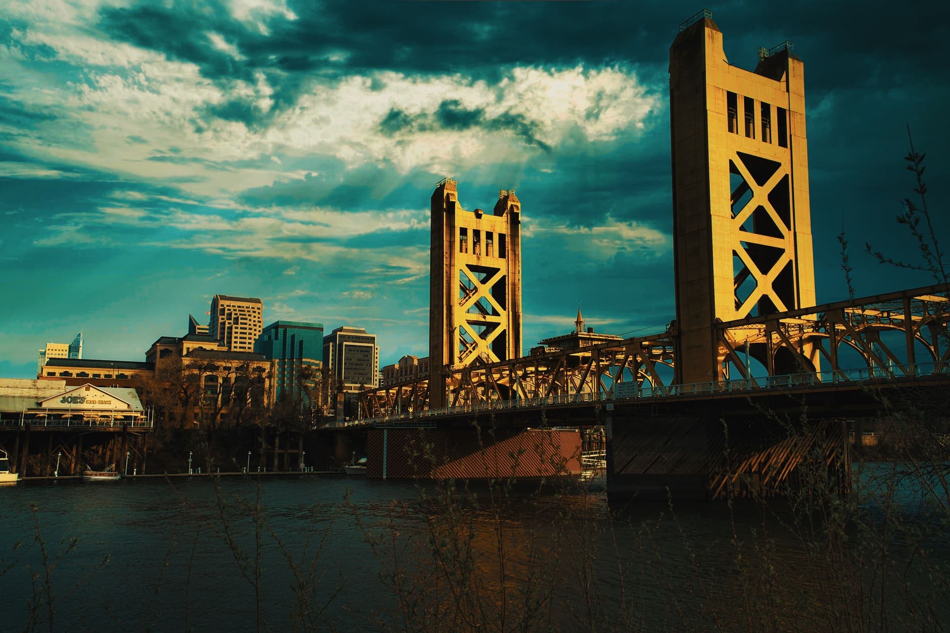 The Tower Bridge lit gold at dusk over the Sacramento River, with the downtown skyline behind it